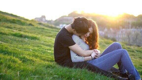 日落时分一对年轻情侣在野外拥抱亲吻