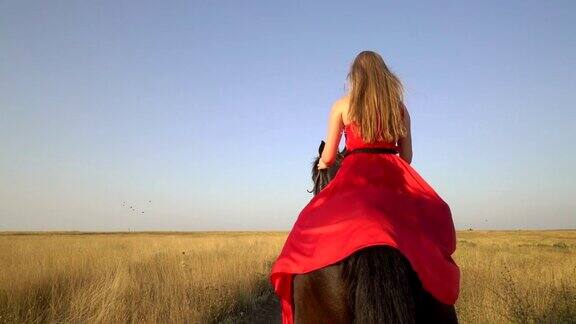 骑马的姑娘穿着红色的长裙在乡间小路上骑马