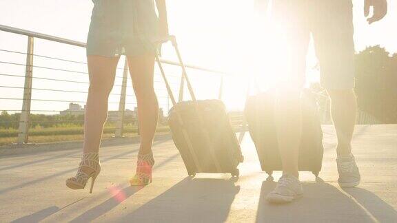 低角度:夏日的日出照在一对带着行李走着的游客夫妇身上