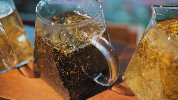 茶壶里的花草茶茶饮料特写镜头三个玻璃茶壶里面有不同的花草五颜六色的茶多叶花碎薄荷青柠菩提树和甘菊茶