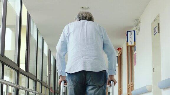 在走廊上用助行器走路的亚洲老人