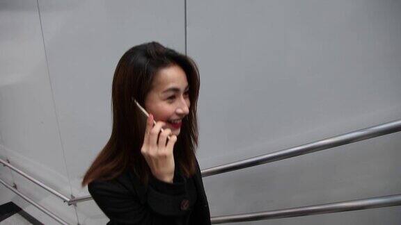 一位亚洲华裔女商务女士从楼梯上下来时正在打电话