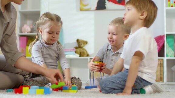 孩子们在幼儿园玩教育玩具和与老师交谈
