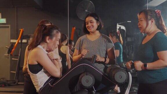 亚洲女性鼓励和支持朋友在健身房做仰卧起坐和其他女性运动员一起锻炼