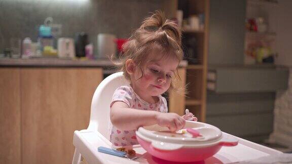 可爱的蹒跚学步的小女孩正在学习如何用叉子吃饭