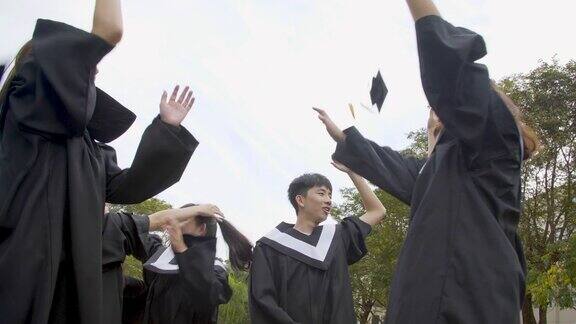 在大学校园里快乐的学生们穿着毕业礼服拿着毕业证书