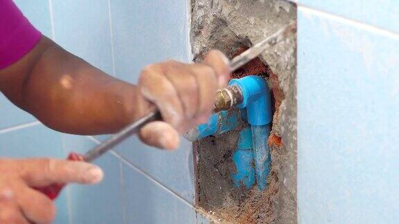 这个工人正在浴室的墙上贴水管