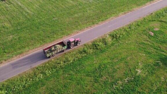 拖拉机载着一拖车干草穿过乡村