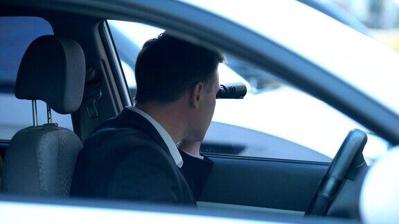 秘密间谍在车里用望远镜看搜索机密情报
