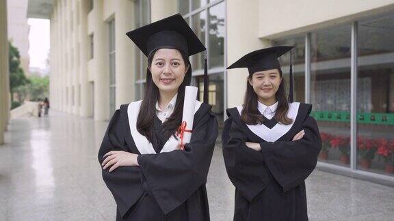 慢动作亚裔日本人快乐的女大学生站在校园传统红砖楼的镜头前欢呼成功在毕业日用拳头举着毕业证书