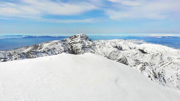 无人机拍摄冬季高山登山队在高海拔山峰的镜头