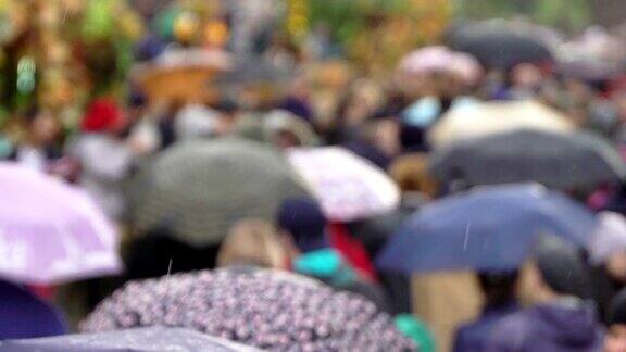 人们在繁忙的商业街撑着雨伞挡雨开始下雨了人们撑开伞真正的时间人们在雨中带着雨伞上下班模糊的散景雨天的城市街道的自然背景