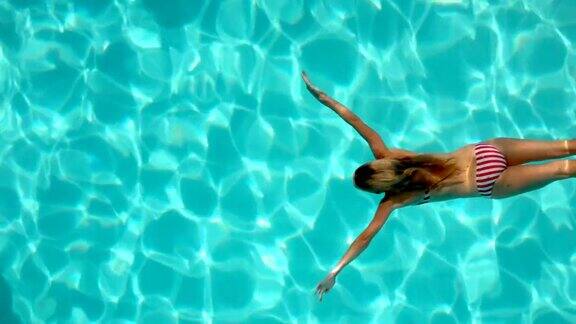 在游泳池里穿比基尼游泳的女人背部视角