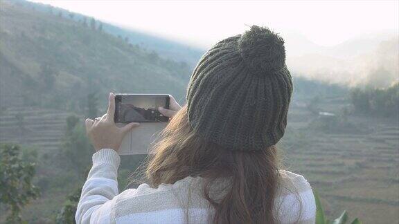 女性用智能手机拍摄视频或照片捕捉美丽的风景