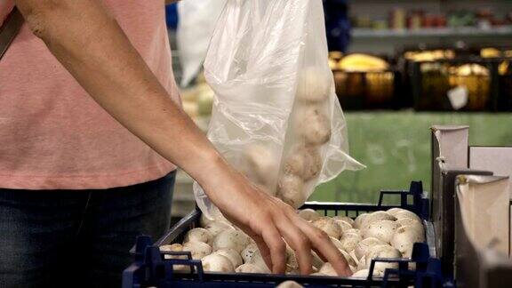 女人在杂货店的农产品部门挑选新鲜的蘑菇