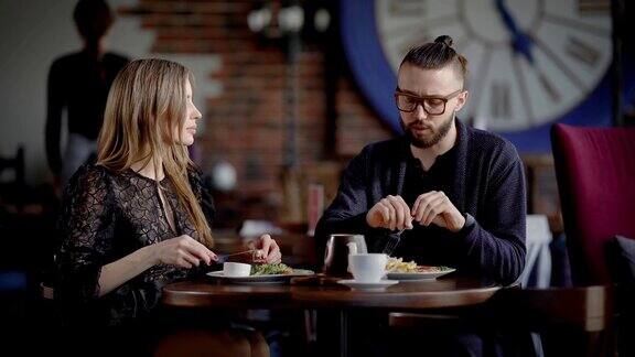 一对夫妇一男一女在现代餐厅里吃午餐或晚餐一个男人和一个女人享受食物和社交交谈在爱情中他们笑是因为他们有约会