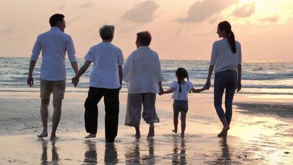 剪影快乐的亚洲大家庭步行到日落的海滩上的海浪家庭生活方式人人寿保险多代人老人假期关系孩子假期退休健康保健理念