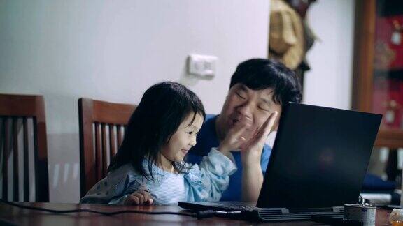 父亲和小女儿(4-5岁)使用笔记本电脑