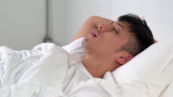 年轻的亚洲男人在床上睡觉时打鼾