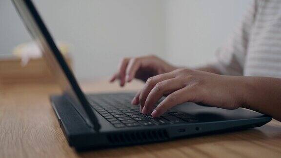 特写的人在家里用笔记本电脑键盘打字