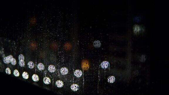 晚上雨点打在窗户上散景灯在背景晚上下大雨