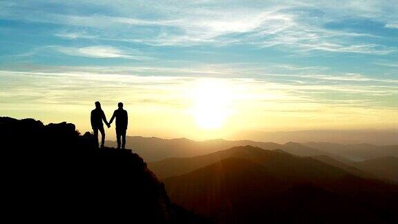 一个男人和一个女人站在山上观看美丽的日出