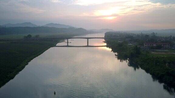 日落时分飞摄像机从宽阔的河流上的高桥上移动
