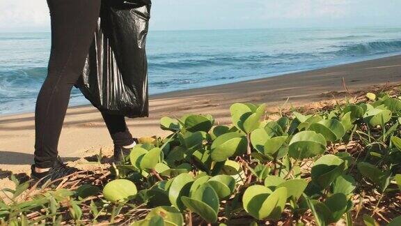 给一个年轻女人打扫卫生在沙滩上捡垃圾