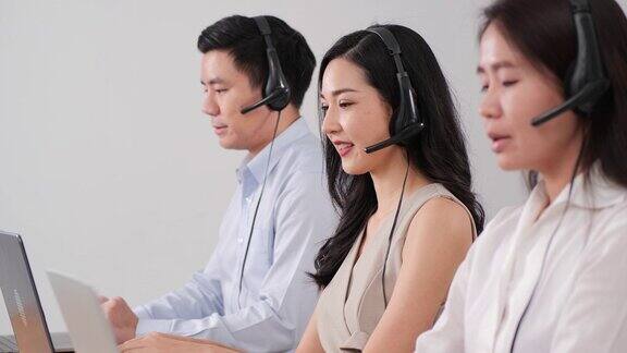 团队客户服务操作员在繁忙的现代呼叫中心工作专家戴着耳机积极地接听电话