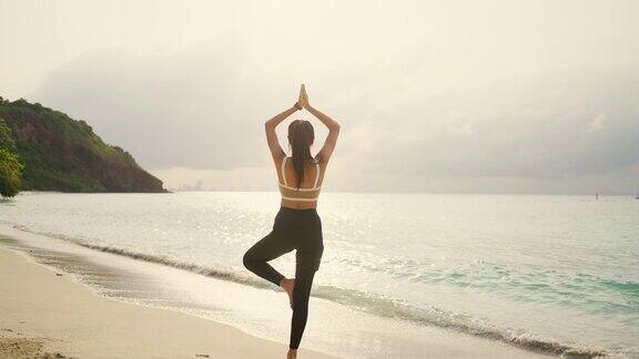 4K亚洲女人早上在海滩做瑜伽运动