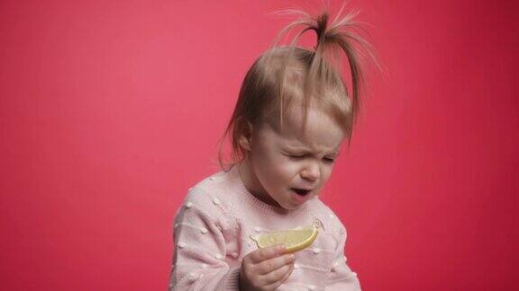 一个可爱美丽的婴儿吃着柠檬一个孩子品尝生柠檬爱玩的小女孩吃水果小孩拿着吃的美味孩子们吃酸柠檬时的表情表情亮眼