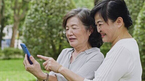 两位台湾资深女性一边看智能手机一边笑