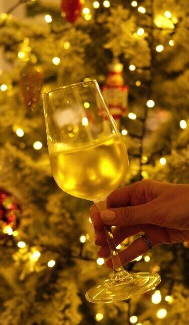 女人拿着一杯白葡萄酒背景是圣诞彩灯