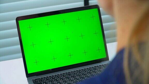 商业女性看绿色屏幕的笔记本电脑