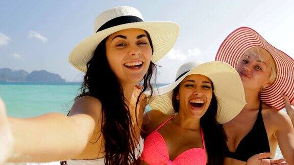在海滩上用手机自拍的女孩快乐的穿着比基尼和草帽的女人在暑假