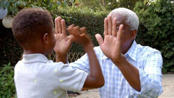 小黑人男孩和爷爷在花园里玩拍手游戏