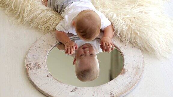 一个可爱的新生婴儿躺在家里的床上玩着镜子