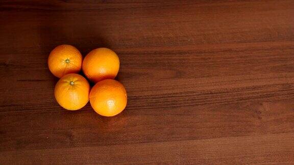 四个成熟多汁的橙子放在棕色的木头表面上