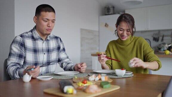 快乐的年轻日本夫妇吃着寿司卷当午餐