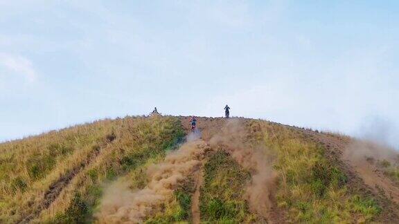两个摩托车越野赛车手在沙尘路上爬山