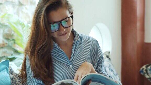 一个年轻女子在酒店的沙发上看杂志