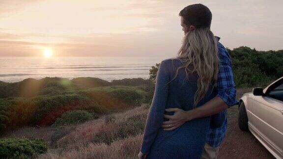浪漫的情侣亲吻时看日落的海洋