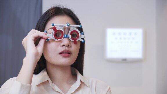 亚洲年轻女子正在调整距离测试框架测试自己的视力阅读视力表Snellen图表准备戴眼镜希望有更好的视力