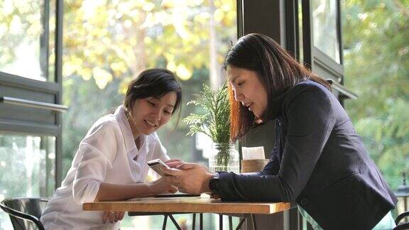 两个女性朋友在咖啡馆一起分享智能手机
