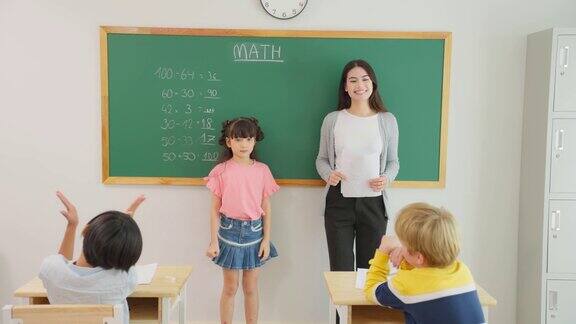 一群小学生在教室里跟着老师学习迷人美丽的女指导老师在幼儿园用快乐有趣的活动为幼儿讲解和教育