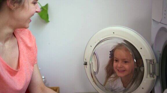 女人和小女孩把脏衣服装进洗衣机里在洗衣机里装满衣服女儿