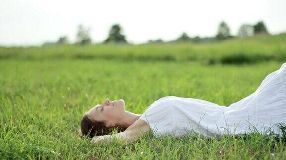 年轻漂亮的黑发女人躺在草地上