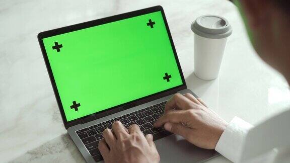 年轻人使用绿色屏幕色度键的笔记本电脑