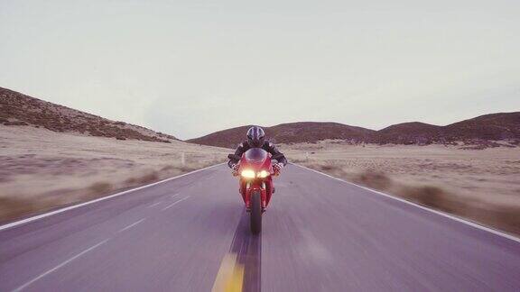 夕阳西下一个骑摩托车的人沿着笔直的乡村公路高速行驶