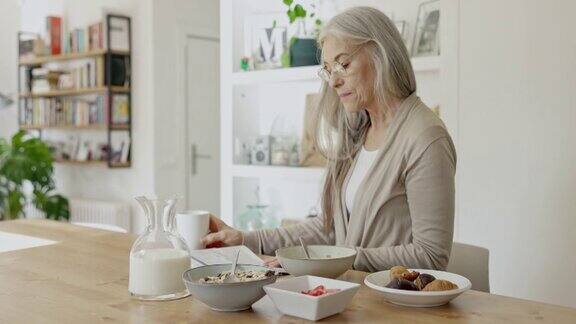 退休白人妇女享受早餐和报纸